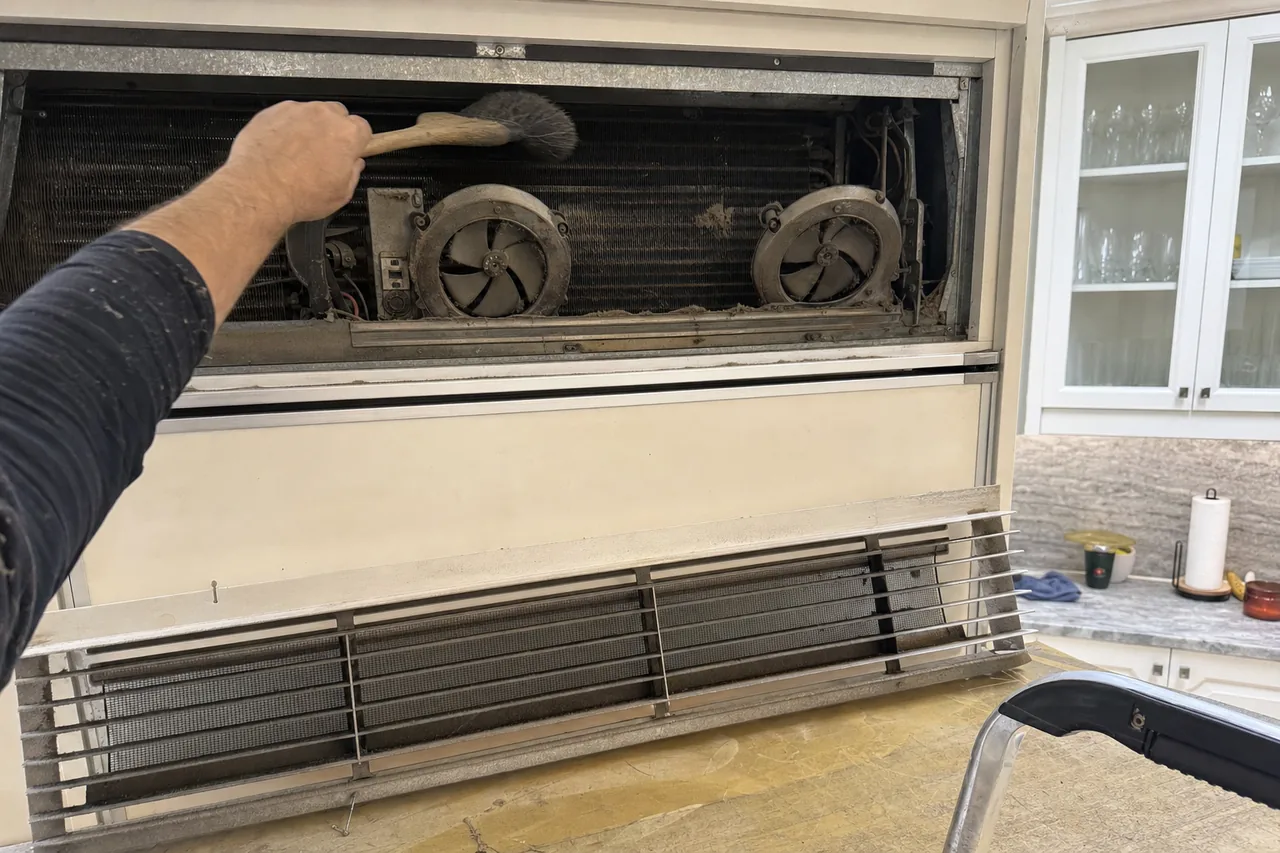 A condenser cleaning seen from the other side — coil, fans and the grille that was lifted out to reach them